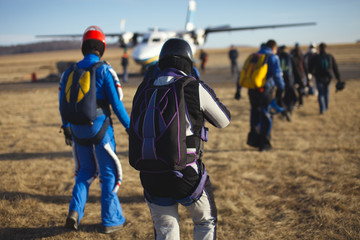 Group of athletes parachutists go to the plane before take-off.