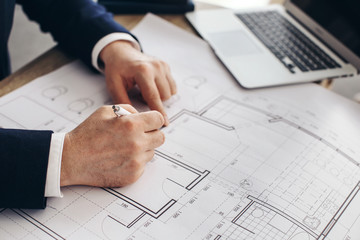 Mature architect working with drawings in office, closeup