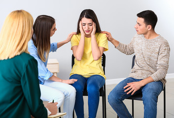 People calming woman at group therapy session
