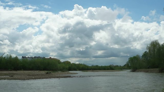Watercourse of the mountain river after heavy rains against the background of the blue sky and white clouds, background