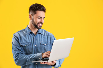 Male programmer with laptop on color background