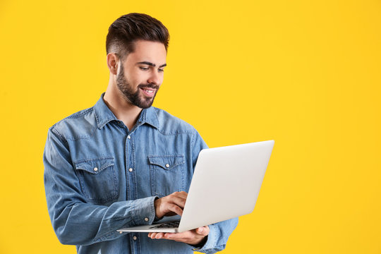 Male programmer with laptop on color background