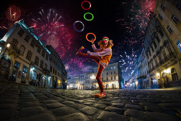 Night street circus performance whit clown, juggler. Festival city background. fireworks and Celebration atmosphere. Wide engle