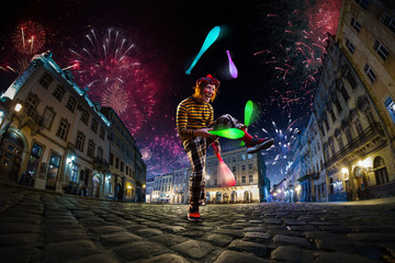 Obraz na płótnie Canvas Night street circus performance whit clown, juggler. Festival city background. fireworks and Celebration atmosphere.