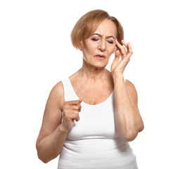 Beautiful mature woman suffering from head ache against white background
