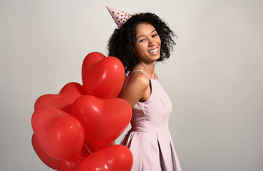 Happy African-American woman with air balloons on grey background