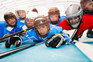 Happy boys in hockey uniform laying on ice rink