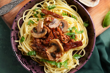 Bowl with tasty boiled pasta and mushrooms on table, closeup