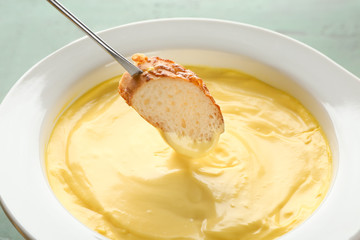 Dipping of bread into cheese fondue, closeup