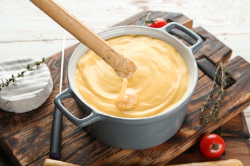 Dipping of bread stick into cheese fondue on table