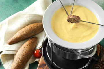 Cheese fondue with piece of bread on table