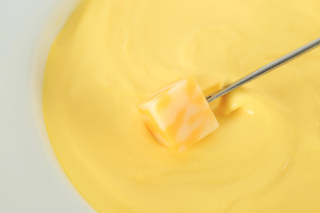 Dipping of cheese into hot fondue, closeup