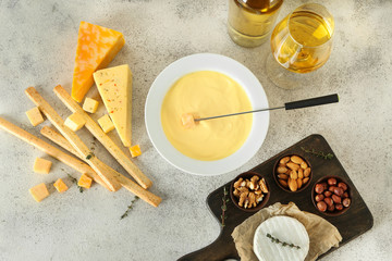 Cheese fondue with snacks and wine on grey background