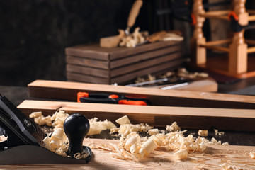 Carpenter's smoothing plane with wooden plank on table in workshop