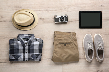 Set of clothes, accessories, tablet computer and photo camera on light wooden background