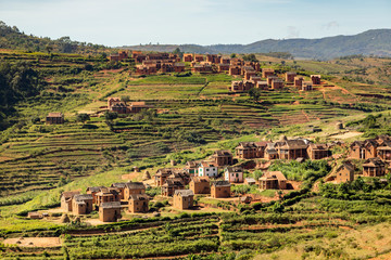 Rural mountain village landscape in Central Madagascar. Traditional red brick houses on hill layers with crop fields and mountains on the backgrounds. 