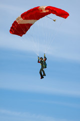 Skydiver with a bright parachute against a sky background with clouds close-up.