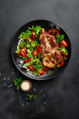 Baked pork steak with fresh vegetable salad on a plate