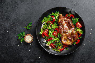 Baked pork steak with fresh vegetable salad on a plate