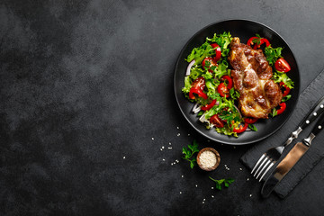 Baked pork steak with fresh vegetable salad on a plate