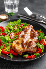 Baked pork steak with fresh vegetable salad on a plate