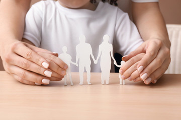 Woman and child with figure of family at table. Concept of adoption