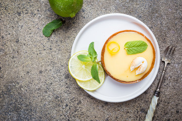 Key lime tarts with fresh lime and mint leaves, top view