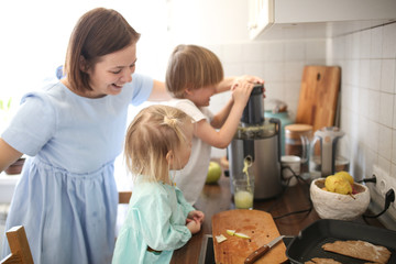 Cute mom and small children with juicer squeeze
