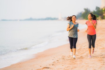 Portrait beautiful young sport asian woman running and exercise on the beach near sea and ocean at sunrise or sunset time