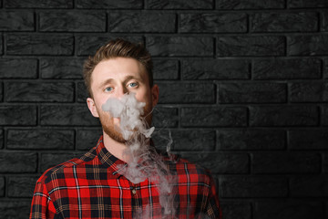 Young man smoking on dark background