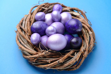 Nest with beautiful Easter eggs on color background