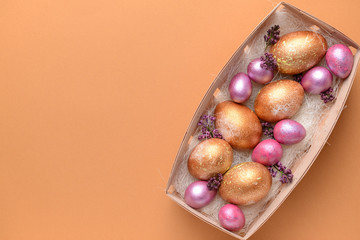 Box with beautiful Easter eggs on color background