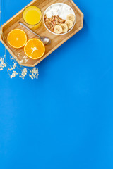 Obraz na płótnie Canvas Bright breakfast with granola and orange juice on blue background top view mockup