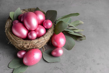Nest with beautiful Easter eggs on grey background