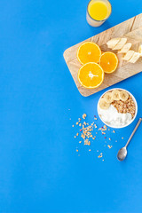 granola with banana slices for breakfast on blue background top view copyspace