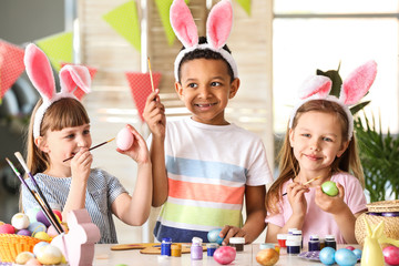 Cute little children painting Easter eggs at home
