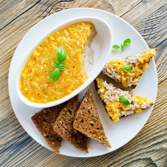 a bowl of chicken rillettes with pineapple and chili jam, open sandwiches with the rillettes, and grain bread slices in white plate on wooden top