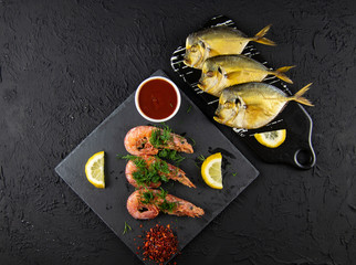 Boiled shrimps and smoked fish with lemons, greens and sauce on a wooden background. Top view