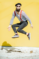 Portrait of a stylish joyful man jumping on the colorful background outdoors