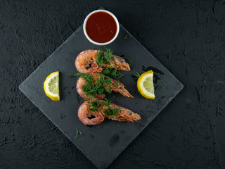 Boiled shrimps with lemons, greens and sauce on a wooden background. Top view