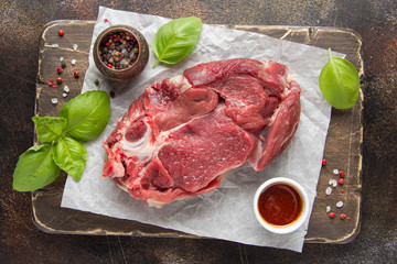 Raw beef on bone, cooking steak with spices, barbecue marinade, red sauce. Traditional food, uncooked meat on Board