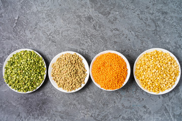 Top view of assortment of peas, lentils and legumes over gray background.