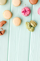 Brignt macarons for sweet break on mint green background top view mock up