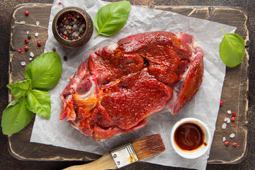 Raw beef on bone, cooking steak with spices, barbecue marinade, red sauce. Traditional food,...