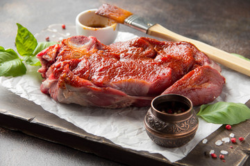 Raw beef on bone, cooking steak with spices, barbecue marinade, red sauce. Traditional food,...