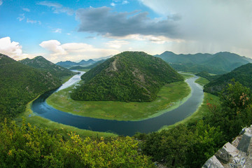 Beautiful mountain landscape with winding river, green forest, thunderstorm and cumulus clouds, top view, Montenegro