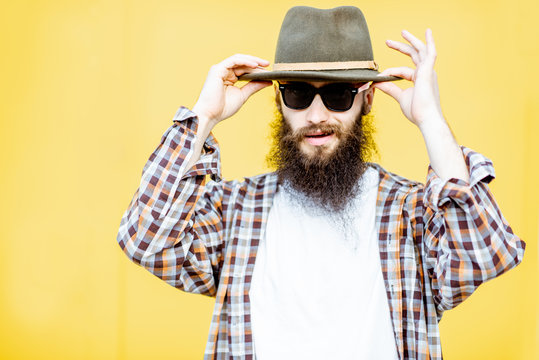 Portrait of a cool stylish man in shirt and hat posing on the bright yellow background