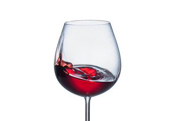 Splashing red wine in a glass goblet on white background
