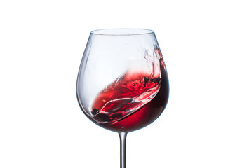 Splashing red wine in a glass goblet on white background
