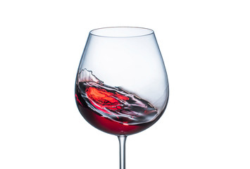 Splashing red wine in a glass goblet on white background